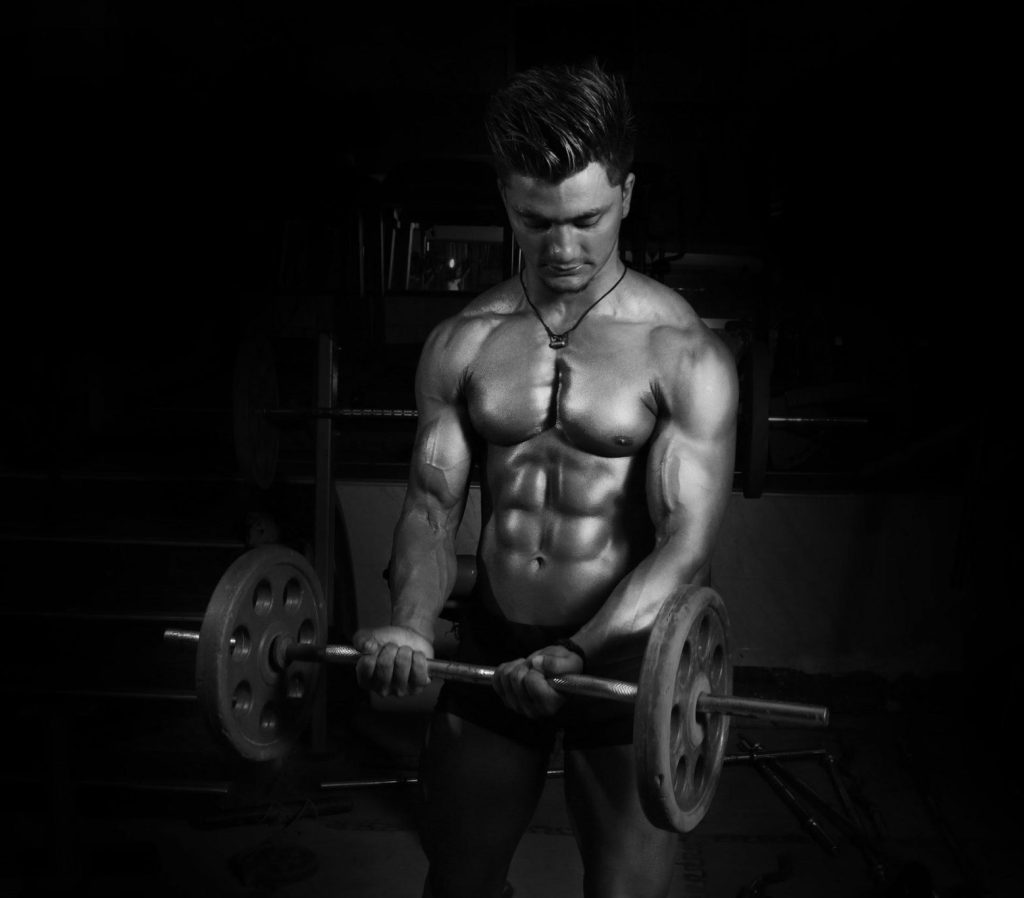 Muscular man lifting a barbell in a gym