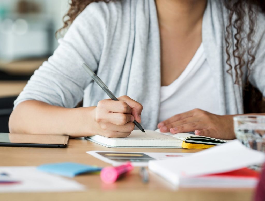 Girl writing notes in a notebook at a desk